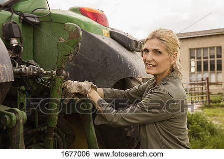Portrait of smiling female farmer standing by agricultural machinery against sky View Large Photo Image Stock Photograph - Portrait of smiling female farmer standing by agricultural machinery against sky. Fotosearch