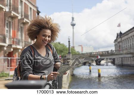 Portrait of smiling female tourist standing with map against Fernsehturm, Berlin, Germany View Large Photo Image Stock Image - Portrait of smiling female tourist standing with map against Fernsehturm, Berlin, Germany. Fotosearch