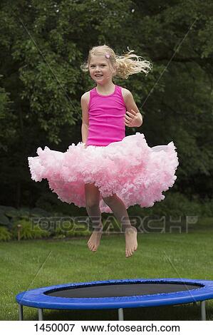 Stock Photo - Portrait of smiling girl jumping on trampoline. Fotosearch