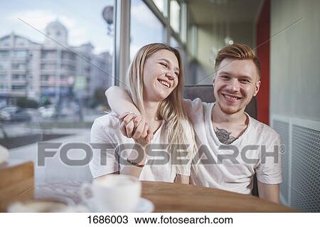 Portrait of smiling man sitting with girlfriend at restaurant View Large Photo Image Stock Image - Portrait of smiling man sitting with girlfriend at restaurant. Fotosearch