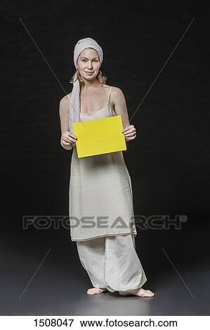 Stock Photo - Portrait of smiling woman holding yellow placard against black background. Fotosearch