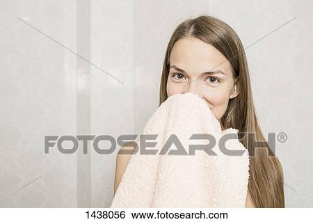 Stock Photograph - Portrait of smiling woman holding towel in domestic bathroom. Fotosearch