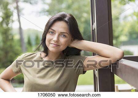 Portrait of smiling woman leaning on railing at yard View Large Photo Image Stock Image - Portrait of smiling woman leaning on railing at yard. Fotosearch