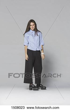 Portrait of smiling woman standing against gray background View Large Photo Image Stock Image - Portrait of smiling woman standing against gray background. Fotosearch