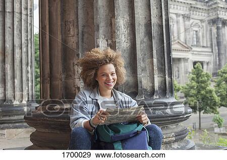Portrait of smiling young Afro female tourist sitting with map against column at Altes Museum View Large Photo Image Stock Photo - Portrait of smiling young Afro female tourist sitting with map against column at Altes Museum. Fotosearch