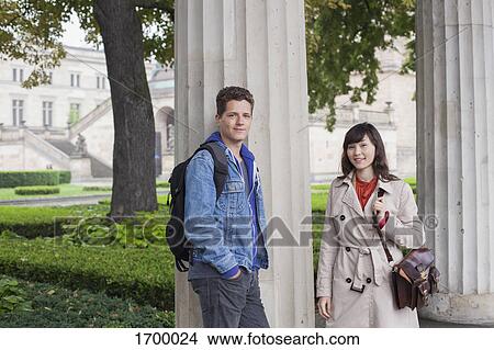 Portrait of smiling young friends standing by column, Berlin, Germany View Large Photo Image Picture - Portrait of smiling young friends standing by column, Berlin, Germany. Fotosearch