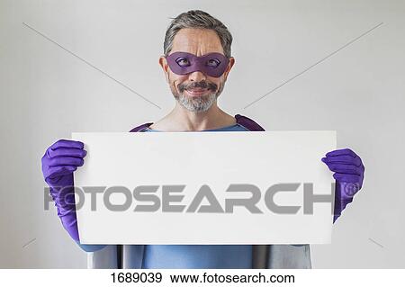Portrait of superhero holding blank placard against white background View Large Photo Image Stock Photo - Portrait of superhero holding blank placard against white background. Fotosearch