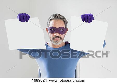Portrait of superhero holding torn blank placard against white background View Large Photo Image Picture - Portrait of superhero holding torn blank placard against white background. Fotosearch