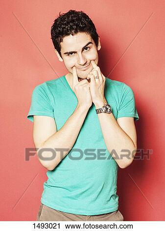 Portrait of upset young man making artificial smile against red background View Large Photo Image Stock Image - Portrait of upset young man making artificial smile against red background. Fotosearch