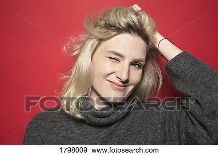 Portrait of woman smiling and winking with hand on head against red background View Large Photo Image Stock Photo - Portrait of woman smiling and winking with hand on head against red background. Fotosearch