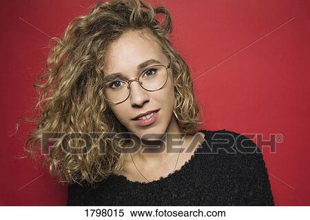 Portrait of woman with curly hair and wearing glasses against red background View Large Photo Image Stock Photography - Portrait of woman with curly hair and wearing glasses against red background. Fotosearch