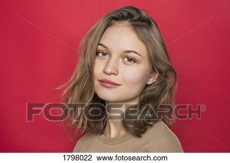 Portrait of woman with light brown hair and smiling against red background View Large Photo Image Stock Image - Portrait of woman with light brown hair and smiling against red background. Fotosearch