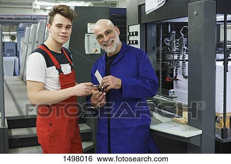 Portrait of workers holding tool and standing at printing press View Large Photo Image Stock Photograph - Portrait of workers holding tool and standing at printing press. Fotosearch
