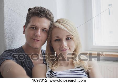 Portrait of young couple sitting at home View Large Photo Image Stock Image - Portrait of young couple sitting at home. Fotosearch