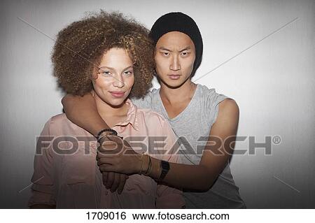 Portrait of young couple standing against white wall View Large Photo Image Stock Photograph - Portrait of young couple standing against white wall. Fotosearch