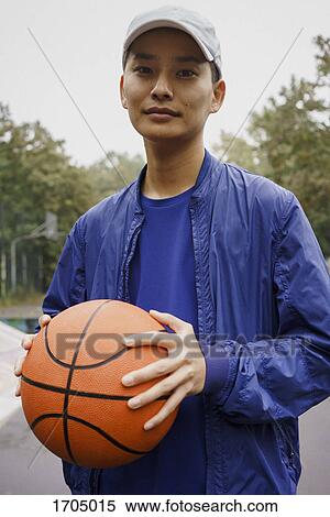 Portrait of young man holding ball while standing at park View Large Photo Image Stock Photography - Portrait of young man holding ball while standing at park. Fotosearch