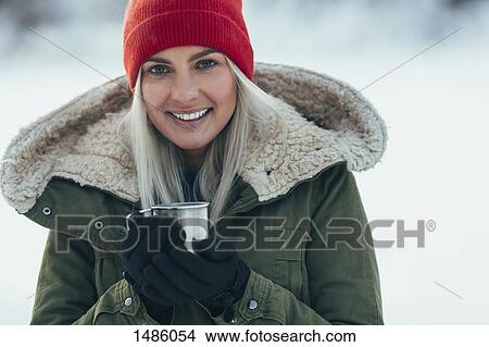 Picture - Portrait of young woman having coffee during winter. Fotosearch