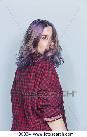 Picture - Portrait of young woman with dyed and tousled hair against blue background. Fotosearch