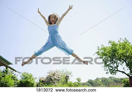 Portrait playful, carefree girl jumping for joy in back yard View Large Photo Image Stock Image - Portrait playful, carefree girl jumping for joy in back yard. Fotosearch