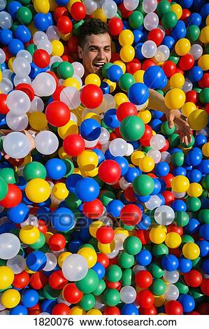 Portrait playful young man laying in multicolor ball pool View Large Photo Image Stock Photograph - Portrait playful young man laying in multicolor ball pool. Fotosearch