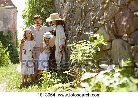 Portrait pregnant family at sunny stone wall in garden View Large Photo Image Picture - Portrait pregnant family at sunny stone wall in garden. Fotosearch