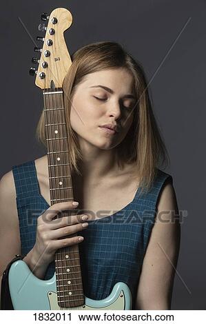 Stock Image - Portrait serene, beautiful young woman with electric guitar. Fotosearch