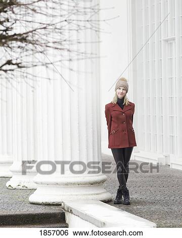Portrait serene woman in coat and knit hat standing at column View Large Photo Image Stock Photograph - Portrait serene woman in coat and knit hat standing at column. Fotosearch