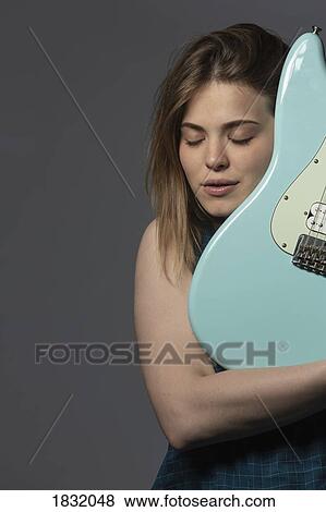 Stock Photo - Portrait serene young woman holding electric guitar. Fotosearch