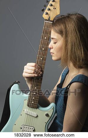 Stock Photo - Portrait serene young woman with electric guitar. Fotosearch