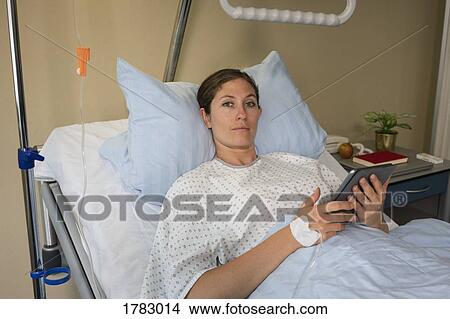 Portrait serious female patient with digital tablet, resting and recovering in hospital room View Large Photo Image Picture - Portrait serious female patient with digital tablet, resting and recovering in hospital room. Fotosearch