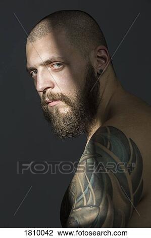 Portrait serious man with beard and tattooed shoulder View Large Photo Image Stock Image - Portrait serious man with beard and tattooed shoulder. Fotosearch