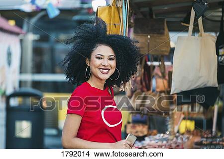 Picture - Portrait smiling, confident young woman shopping at market stall. Fotosearch