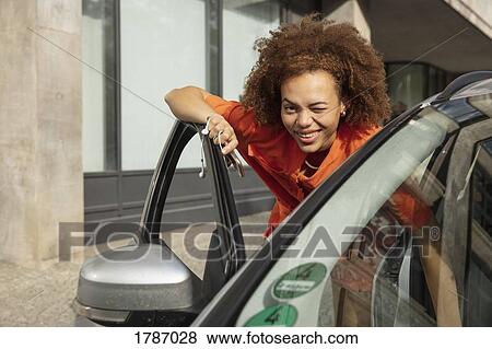 Stock Photo - Portrait smiling, confident young woman winking, getting into car. Fotosearch