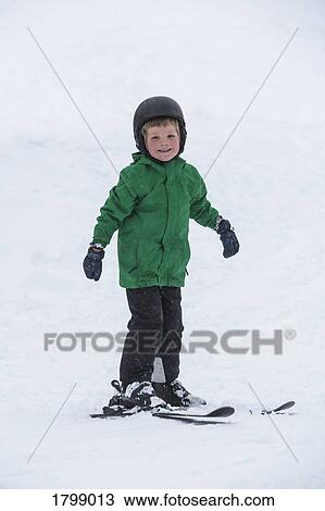 Stock Image - Portrait smiling, cute boy skiing in snow. Fotosearch