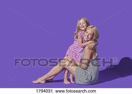 Portrait smiling mother and daughter in striped dresses hugging against purple background View Large Photo Image Stock Image - Portrait smiling mother and daughter in striped dresses hugging against purple background. Fotosearch