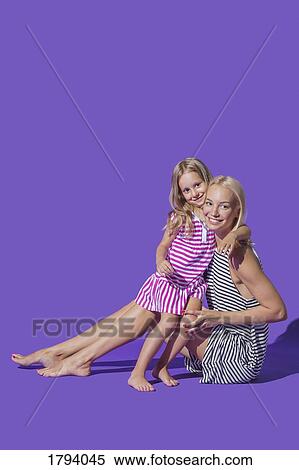 Portrait smiling mother and daughter hugging in striped dresses against purple background View Large Photo Image Stock Photography - Portrait smiling mother and daughter hugging in striped dresses against purple background. Fotosearch