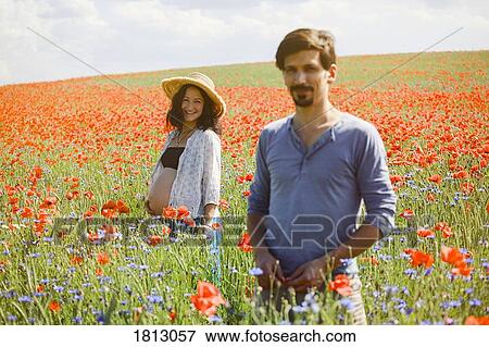 Portrait smiling pregnant couple in sunny, idyllic rural red poppy field View Large Photo Image Stock Photo - Portrait smiling pregnant couple in sunny, idyllic rural red poppy field. Fotosearch