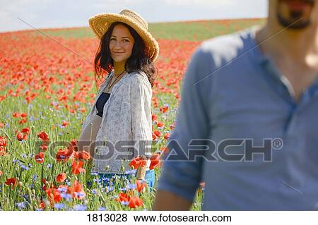 Stock Photo - Portrait smiling pregnant woman standing in sunny, rural red poppy field. Fotosearch