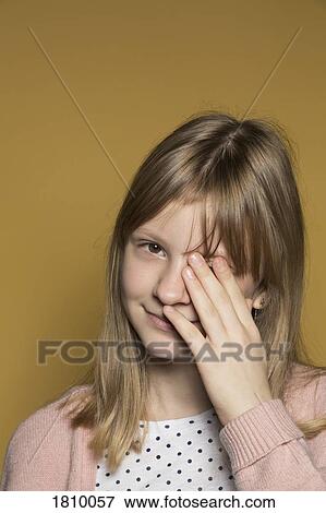 Stock Photo - Portrait smiling tween girl covering eye with hand. Fotosearch