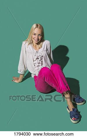 Portrait smiling woman sitting against green background View Large Photo Image Stock Image - Portrait smiling woman sitting against green background. Fotosearch