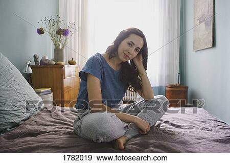 Stock Photo - Portrait smiling woman sitting on bed. Fotosearch
