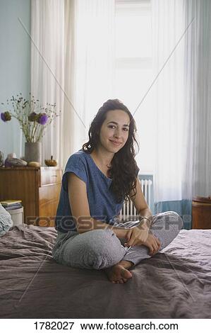 Stock Photo - Portrait smiling woman sitting on bed. Fotosearch