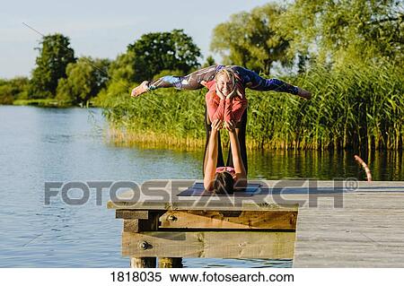 Portrait smiling women practicing acro yoga on sunny lakeside dock View Large Photo Image Stock Photography - Portrait smiling women practicing acro yoga on sunny lakeside dock. Fotosearch