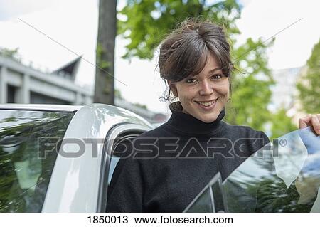 Portrait smiling young woman standing at car door View Large Photo Image Stock Image - Portrait smiling young woman standing at car door. Fotosearch