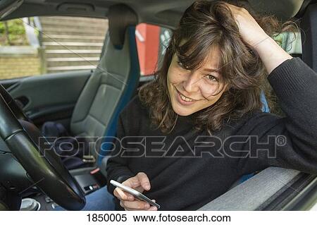 Portrait smiling young woman using smart phone in car View Large Photo Image Stock Photography - Portrait smiling young woman using smart phone in car. Fotosearch