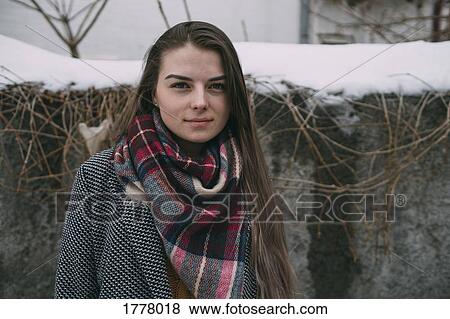 Stock Photo - Portrait young woman in plaid scarf against snow covered wall. Fotosearch