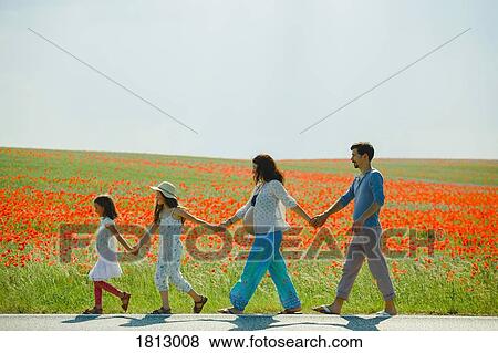 Pregnant family holding hands, walking along sunny, rural red poppy field View Large Photo Image Stock Photo - Pregnant family holding hands, walking along sunny, rural red poppy field. Fotosearch