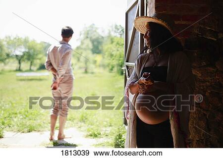 Pregnant woman watching man in barn doorway View Large Photo Image Stock Photo - Pregnant woman watching man in barn doorway. Fotosearch