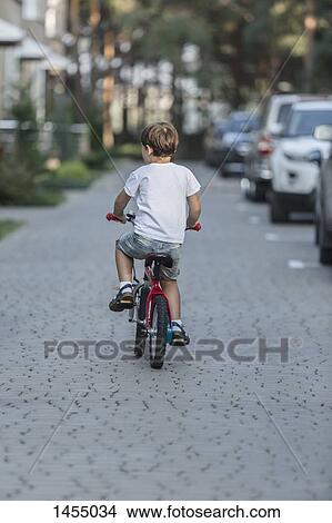 Rear view of boy riding bicycle on street View Large Photo Image Picture - Rear view of boy riding bicycle on street. Fotosearch