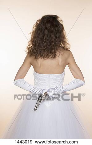 Rear view of bride holding handgun against colored background View Large Photo Image Stock Photo - Rear view of bride holding handgun against colored background. Fotosearch
